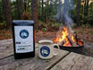 Coffee bag and mug with Taylor's Trail logo by a campfire in a forest setting